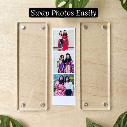 Acrylic photo magnet strip kept open on a wooden surface with a photo paper sheet displaying photos of people.