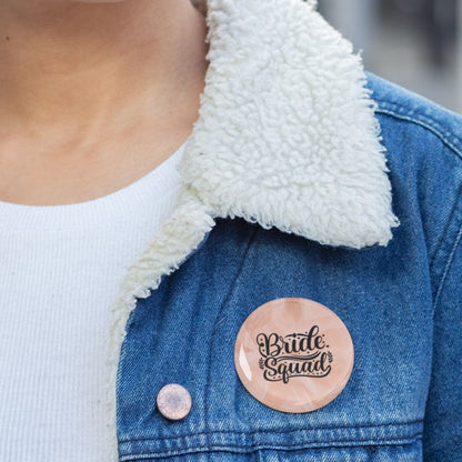 Person wearing a denim jacket with a 'Bride Squad' pin badge