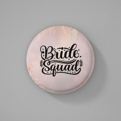 Round pink color button badge with 'Bride Squad' text on a gray background