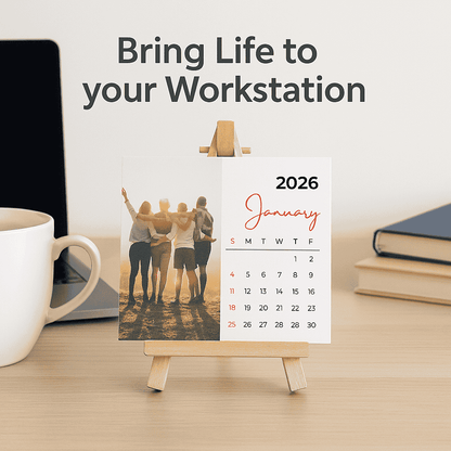 Small easel with a calendar on a desk with a mug, laptop, and books.